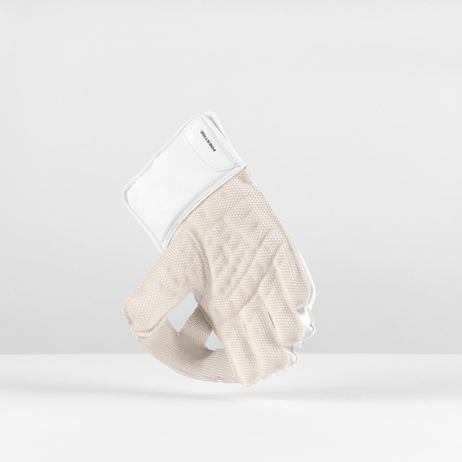 The Gray Nicolls Classic Prestige WK Gloves 2026 stand upright on a white surface, featuring a beige knit design with a white cuff and Velcro closure, and provide dependable impact protection against a plain white background.