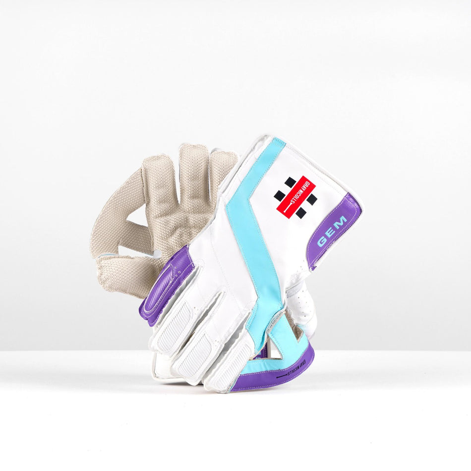 The Gray Nicolls Classic GEM WK Gloves 2026 are white wicket-keeping gloves with purple, blue, and turquoise accents, featuring Pro Palm Fit for comfort and a premium PU finish. A red and black Gray Nicolls logo appears on the wrist.