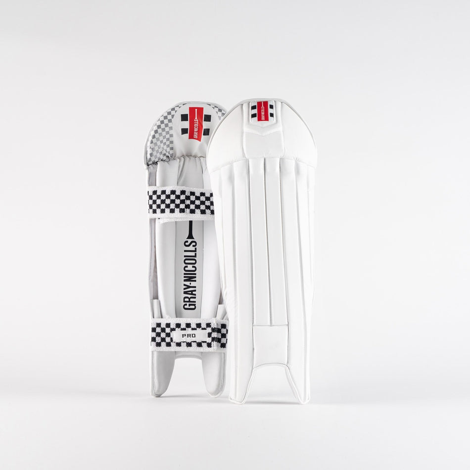 Two Gray Nicolls Pro Wicket Keeping Pads 2026 in white, featuring black and white checkered straps and red branding, stand upright against a plain white background, providing HDF foam protection for lightweight performance.