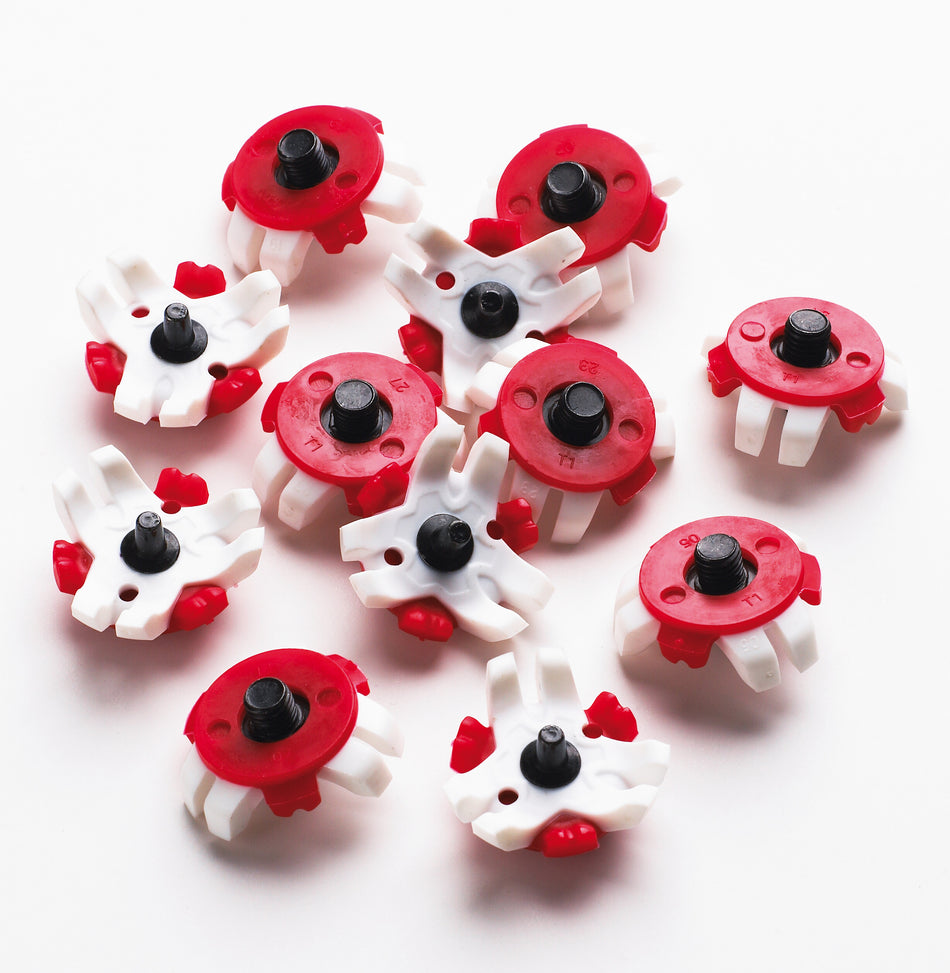 Twenty small plastic pieces with circular red bases, white details, and black cylindrical centers, identified as Gray Nicolls Test Flex Spikes (20) by Gray Nicolls, are scattered on a white surface.