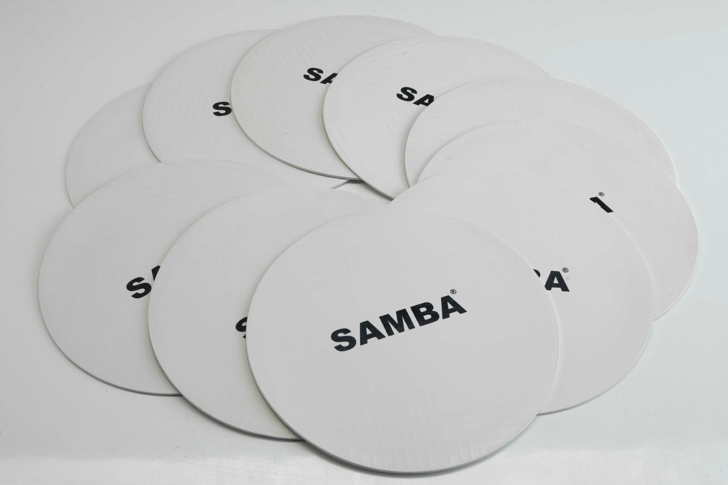 A stack of white Flat Disc Markers by Samba Sports, each printed with the brand name in black, arranged overlapping on a white surface. These non-slip markers are perfect for training session positioning.