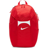 The Nike Academy Team Backpack in Red/White features Storm-FIT rain protection, a white swoosh logo, top handle, side pockets, and zippered compartments.