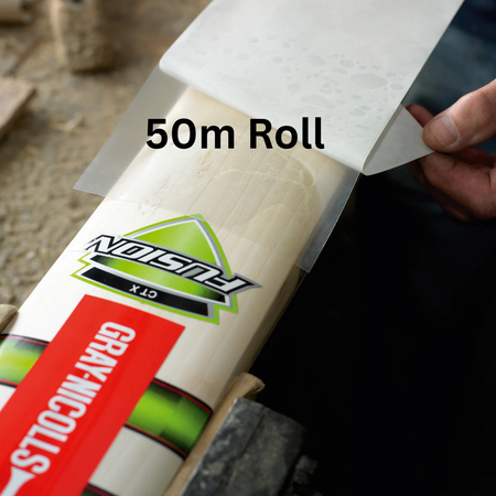 A person applies Gray-Nicolls Extratec self-adhesive PU bat facing from a 50-meter roll onto a Gray Nicolls Fusion cricket bat, protecting its surface as it rests securely on a workbench.