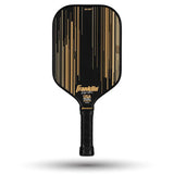 The Franklin Signature Pro Series Pickleball Paddle by Franklin features a black/gold design with gold vertical lines and logo, textured grip handle, MaxGrit surface technology, and "USA Pickleball Approved" printed near the bottom.