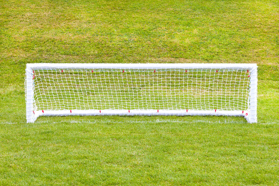 A pair of 8ft x 2ft Mini Hockey Goals by Samba Sports, complete with nets, stands on a green grassy field. The well-maintained turf behind the goals is slightly elevated.