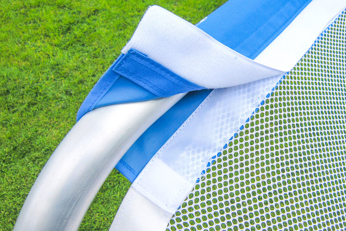 Close-up of a blue and white mesh net attached to the curved metal frame of the Samba Sports Aluminium Folding Football Goal (5ft x 3ft), set against a green grassy field.