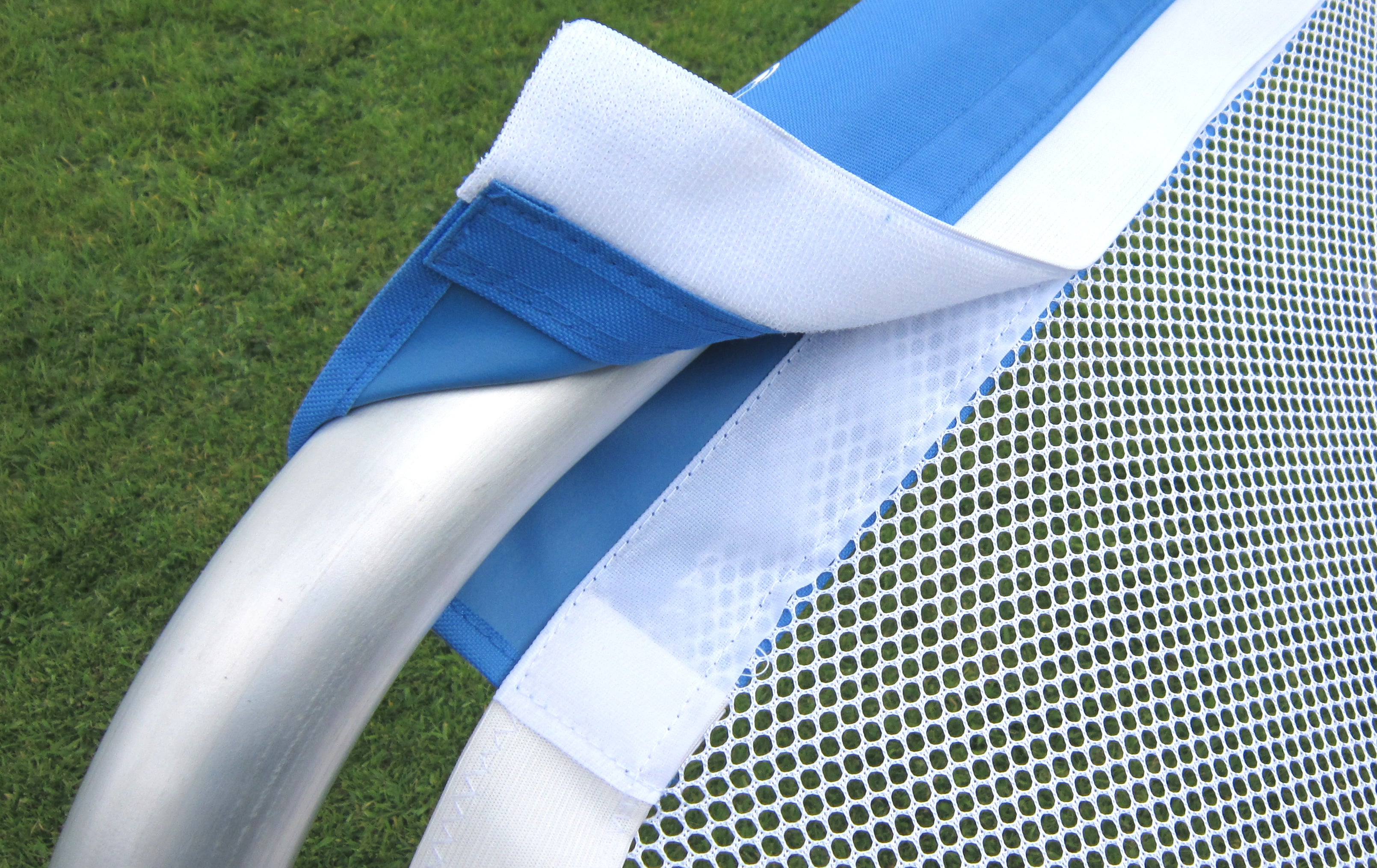 Close-up of a Samba Sports Samba 3v3 4ft x 2.5ft Aluminium Folding Football Goal, showing the white mesh net attached to a silver frame with blue and white straps on green grass.