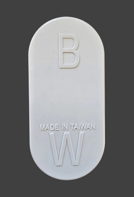 A white, oval tablet resembling a Gray Nicolls Umpires Counter, showing "B" at the top, "MADE IN TAIWAN" in the center, and "W" at the bottom, is displayed against a dark gray background. Brand: Gray Nicolls.