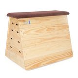 The Niels Larsen Traditional Vault Box - Hide Top by Niels Larsen features a slightly slanted wooden shape with rounded edges, a padded natural hide top, side handholds, interlocking corner blocks for stability, and optional castors for easy mobility.