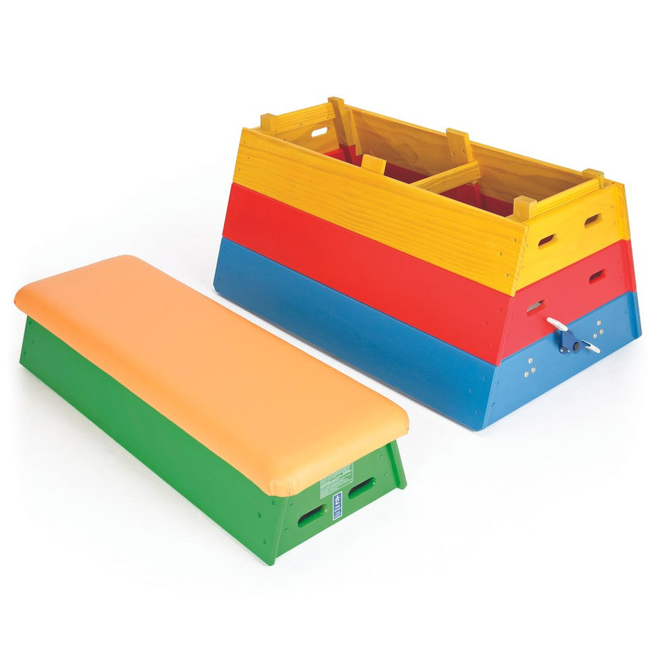 The Niels Larsen Activvault Box by Niels Larsen is a junior gymnastics vault with a padded top, disassembled into four stacked sections in yellow, red, blue, and green, plus a separate orange and green padded bench.