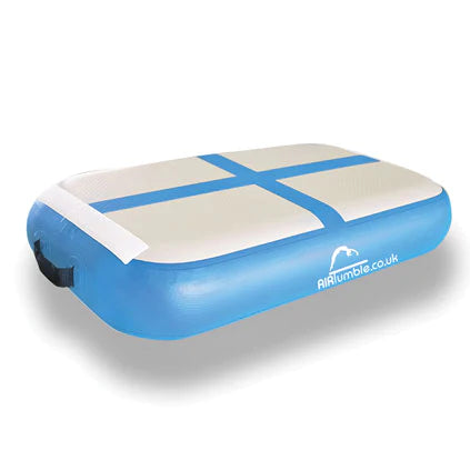 The Niels Larsen Airtumble Airblock is a rectangular blue and white inflatable air track featuring two black side handles, enhanced rebound power, a white cross design on top, and the Niels Larsen logo printed on the side.