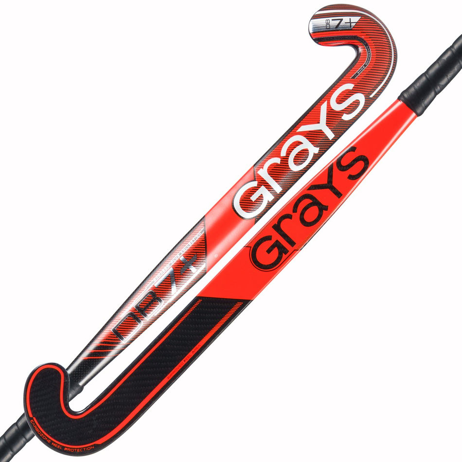 Two red and black Grays DB7+ Hockey Sticks are shown, one front and one back. Each displays the Grays logo, features a curved Dynabow Plus design with Graphene reinforcement, and has black grip tape on the handle.