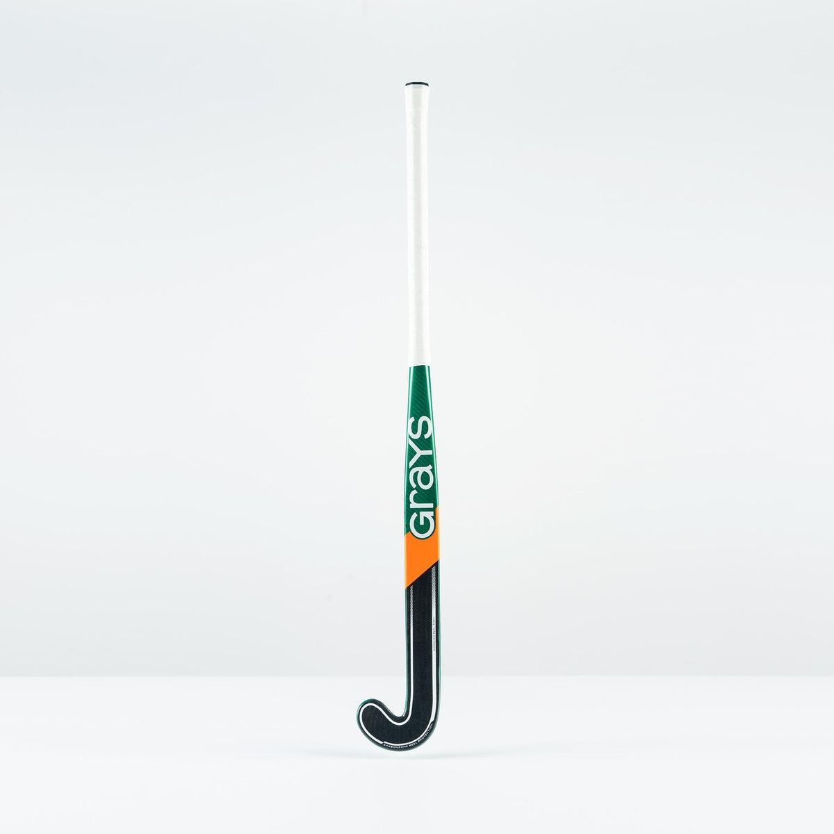 The Grays PB 7+ Junior Hockey Stick 2026 is a black graphene stick with a white handle and green and orange accents. "Grays" is printed vertically on the shaft, offering intermediate power and supreme control against a white background.