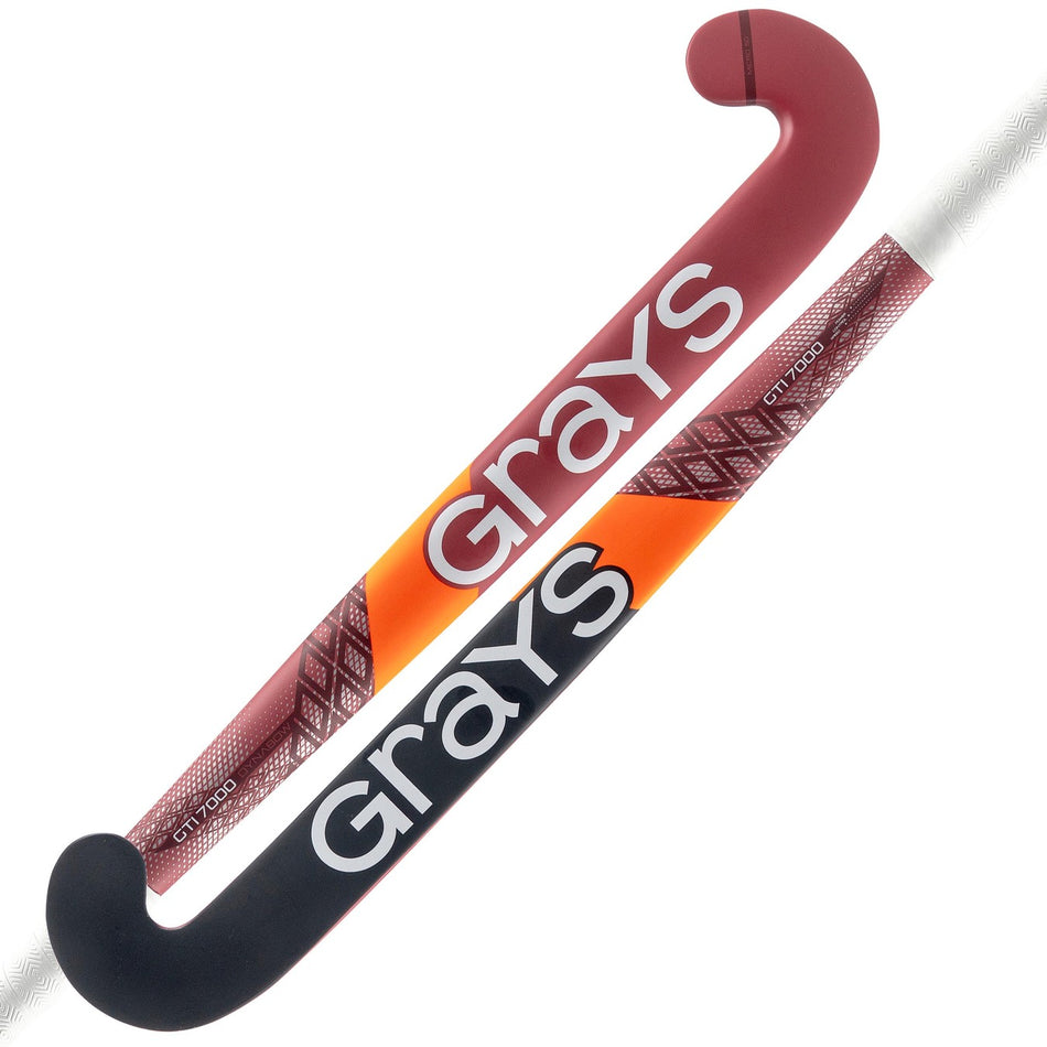 Two Grays GTI7000 Dynabow Indoor Hockey Sticks, one mainly red and the other black-orange, are displayed side by side, each boldly featuring the Grays brand in white.