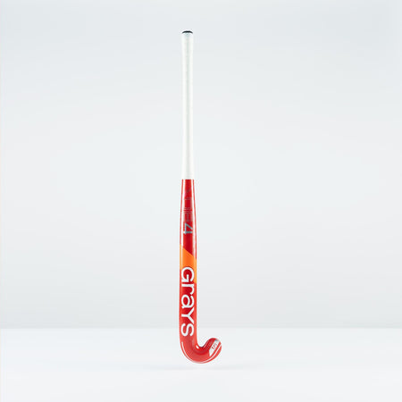 The Grays DB 4 Junior Hockey Stick 2026 features a red and orange design, Dynabow blade profile, white grip, and large Grays branding—standing upright on a plain white background for enhanced 3D skill execution.