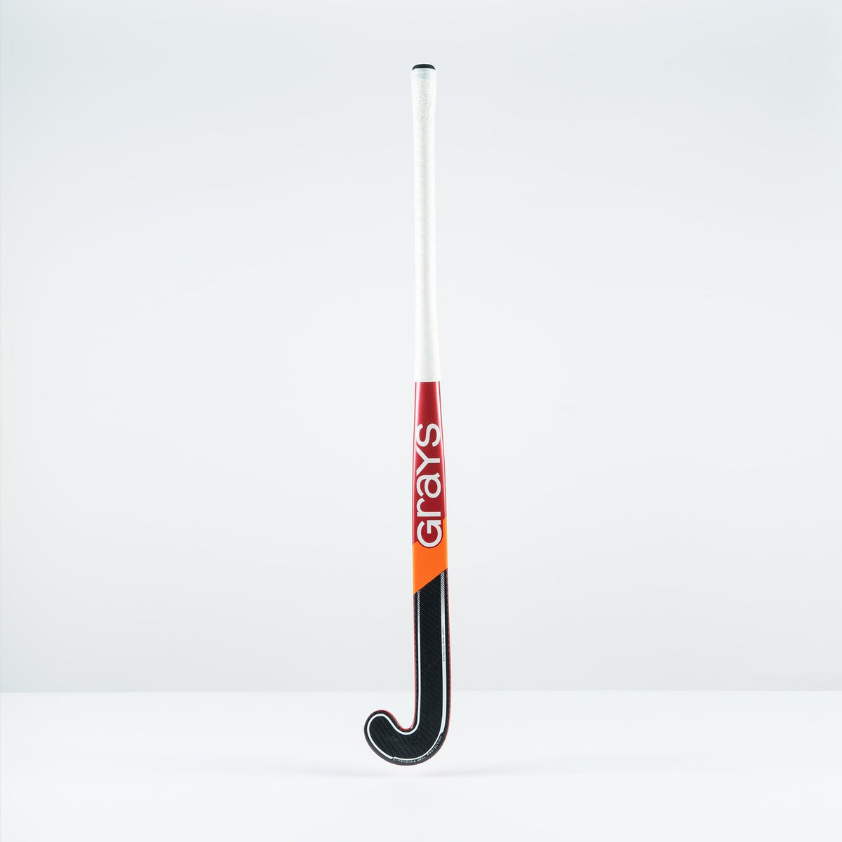 The Grays DB 4 Senior Hockey Stick 2026 stands upright against a plain background, featuring a white handle, black curved end, red and orange accents, Dynabow blade profile, Graphene construction, and "Grays" printed vertically on the shaft.