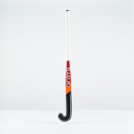 The Grays DB 4 Senior Hockey Stick 2026 stands upright against a plain background, featuring a white handle, black curved end, red and orange accents, Dynabow blade profile, Graphene construction, and "Grays" printed vertically on the shaft.