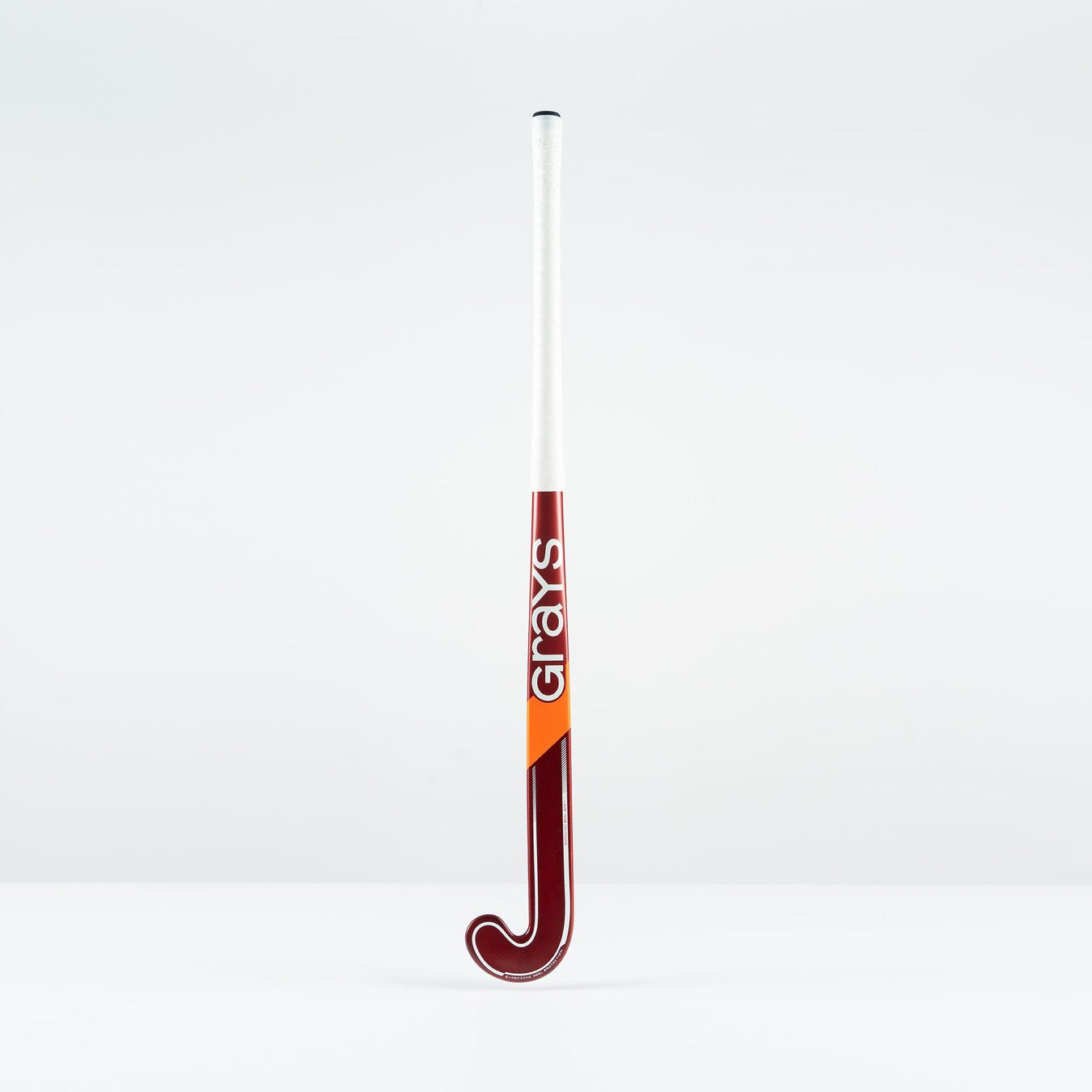 The Grays GT 5 Senior Hockey Stick 2026 stands upright against a white background, showcasing a maroon curved head and shaft with Grays branding in white, an orange diagonal stripe, and a high bow apex for intermediate power and control.