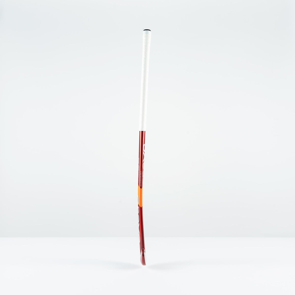 The Grays GT 5 Senior Hockey Stick 2026, in red and white with a high bow apex, stands upright on a white surface, providing intermediate power and control against a plain light gray background.