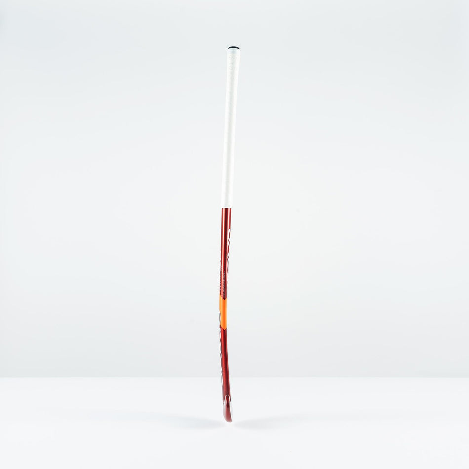 The Grays GT 5 Senior Hockey Stick 2026, in red and white with a high bow apex, stands upright on a white surface, providing intermediate power and control against a plain light gray background.