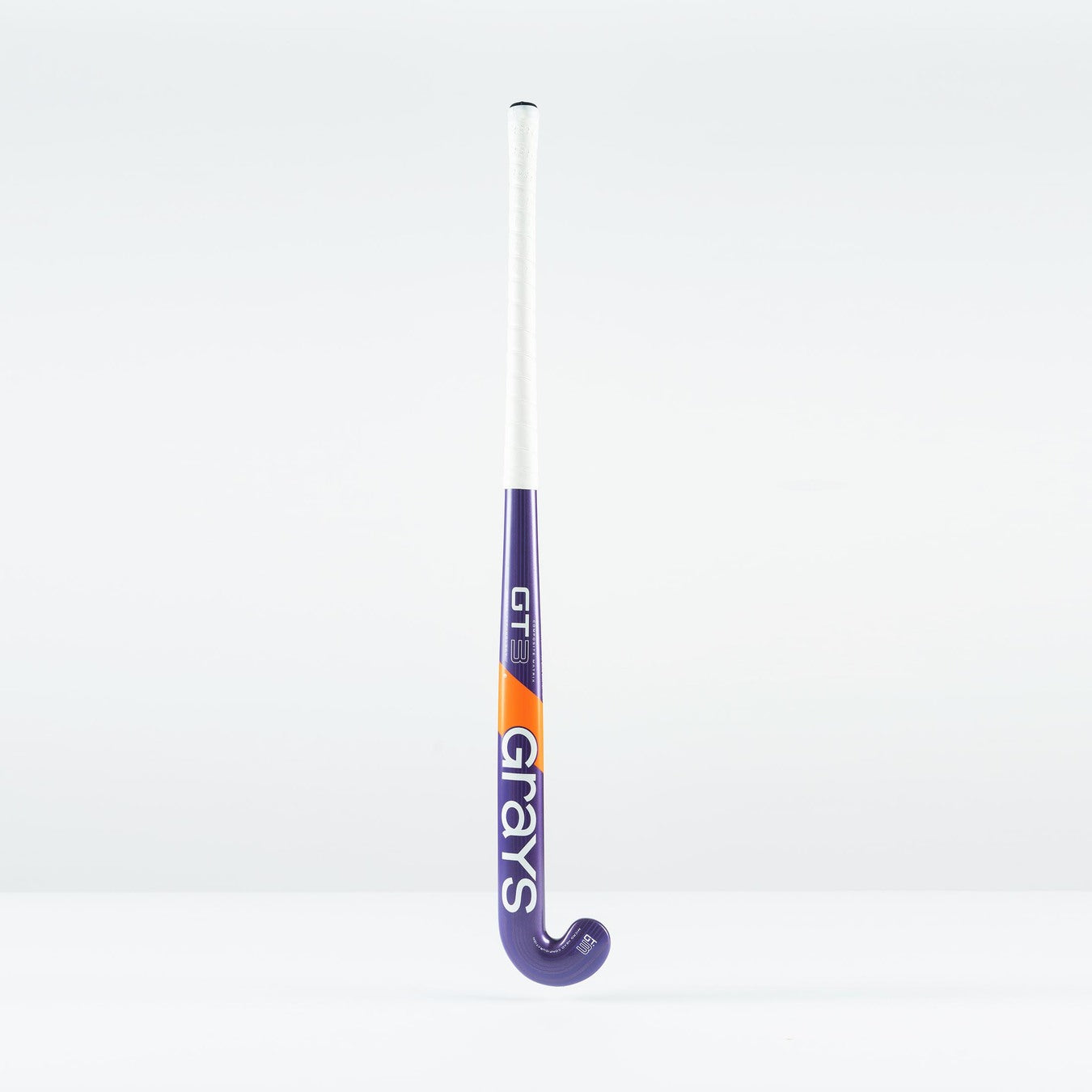 The Grays GT 3 Junior Hockey Stick 2026, in purple with a white grip and orange accents, displays the Grays brand on the shaft. Designed for balanced power and control, it stands upright against a plain white background.