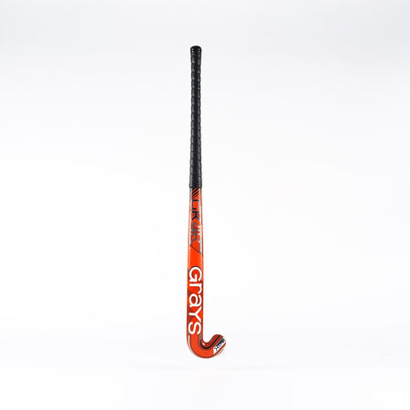 The Grays GK4K Elite Hockey Stick, a red stick with a black grip handle and reinforced mid-section, stands upright against a plain white background.