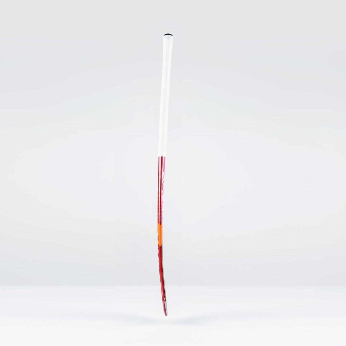 The Grays DB7Xi Dynabow Indoor Senior Hockey Stick 2026 stands upright against a light gray background, showcasing its white grip, red shaft, and orange tip—its sleek design reflecting the all-round skills of the renowned Dynabow blade.