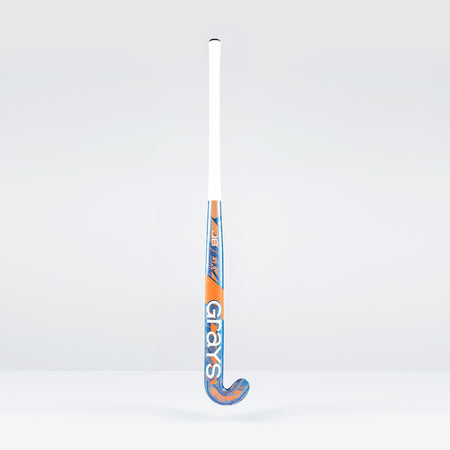 The Grays JB6GXi Jumbow Indoor Senior Hockey Stick stands upright against a plain light background, displaying its white handle and orange-blue shaft with bold GRAYS branding, designed for effective drag flicking.
