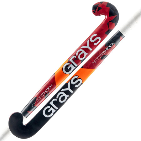 The Grays Aftershock Wooden Hockey Stick, designed for young players, comes in red and black with classic bow shape and white handle, featuring stylish geometric and orange accents.