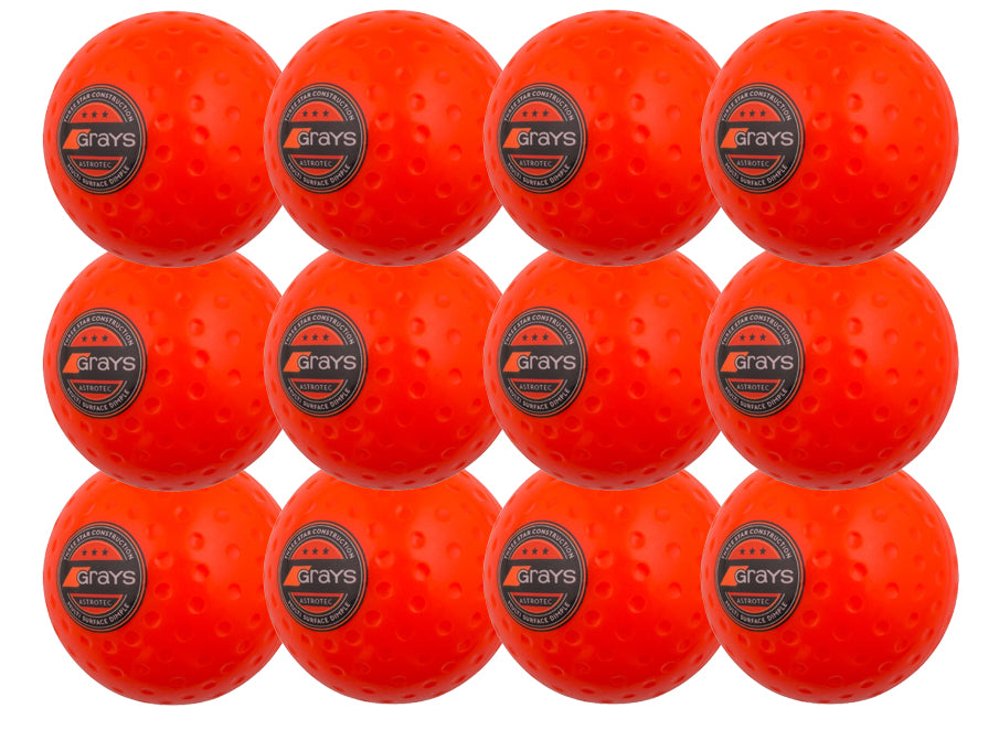 The Grays Astrotec 12 Ball Pack includes twelve bright orange dimpled PVC hockey balls, ideal for synthetic pitches. Each ball features black and silver Grays logos on a white background and is arranged in a 4 by 3 grid.