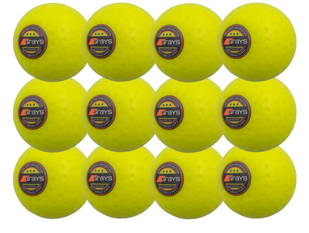 The Grays Astrotec 12 Ball Pack features twelve bright yellow dimpled PVC hockey balls, each with the Grays logo, arranged in a 3x4 grid—perfect for synthetic pitches.