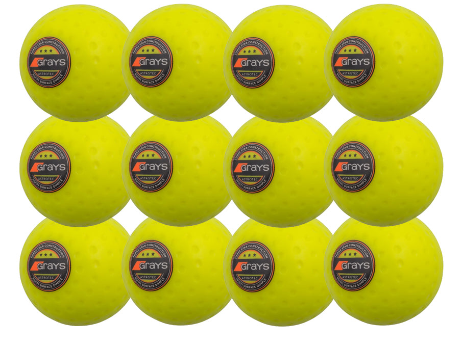 The Grays Astrotec 12 Ball Pack features twelve bright yellow dimpled PVC hockey balls, each with the Grays logo, arranged in a 3x4 grid—perfect for synthetic pitches.
