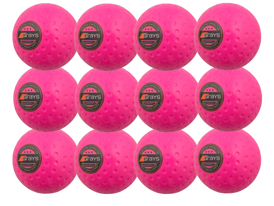 The Grays Astrotec 12 Ball Pack includes twelve bright pink dimpled PVC hockey balls for synthetic pitches, each displaying the black and orange Grays logo, neatly arranged in a 4x3 grid.