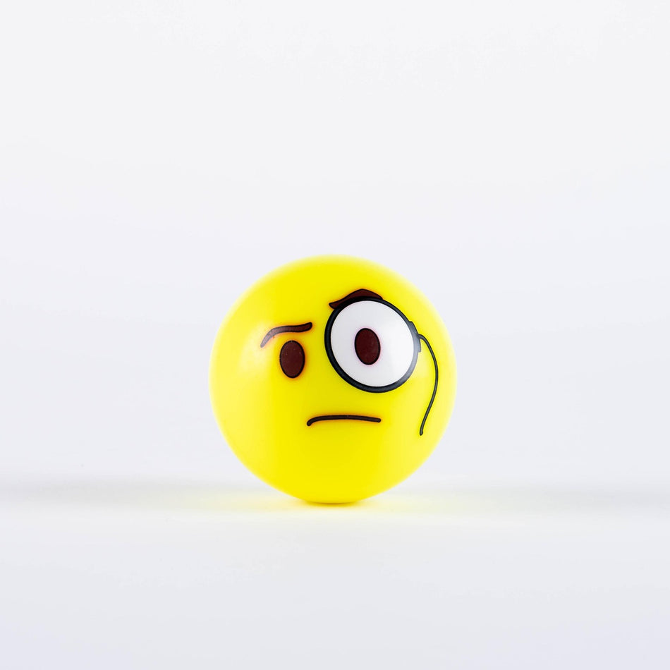 The Grays Emoji Hockey Ball by Grays features a yellow design with a raised eyebrow, monocle, and frown for a quirky, inquisitive look—making it the perfect 2025 hockey player gift. Shown on a plain white background.