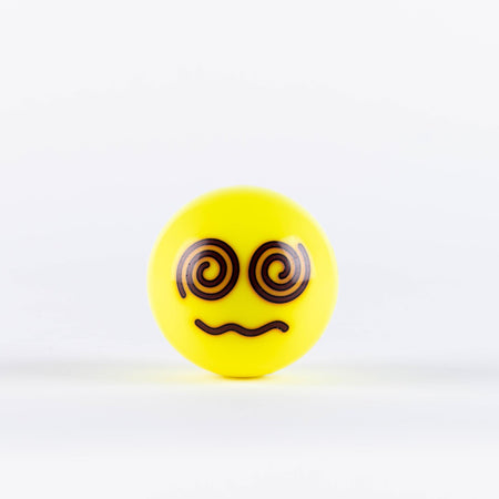The Grays Emoji Hockey Ball by Grays features a yellow ball with a confused face—spiral eyes and wavy mouth—from the Emoji Balls collection, making it a fun 2025 hockey gift, shown on a plain white background.