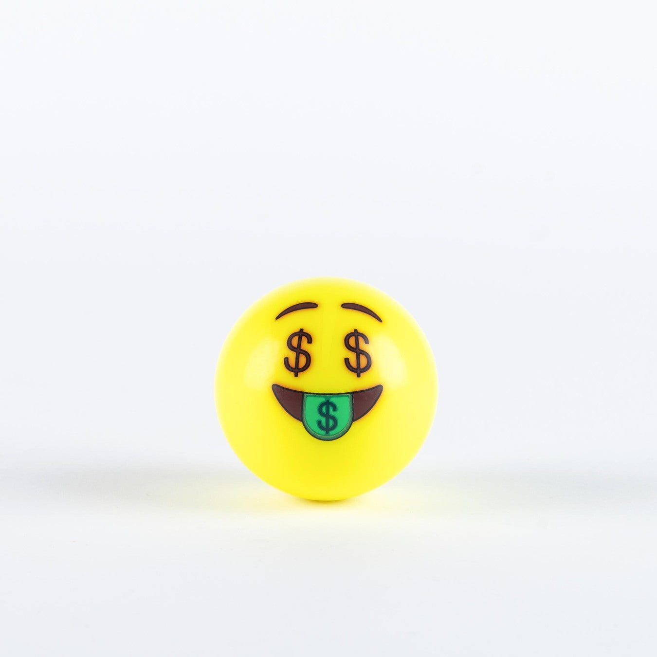 The Grays Emoji Hockey Ball by Grays features a yellow ball with an emoji face showing dollar sign eyes and a green tongue with a dollar symbol—ideal as a 2025 hockey player gift.