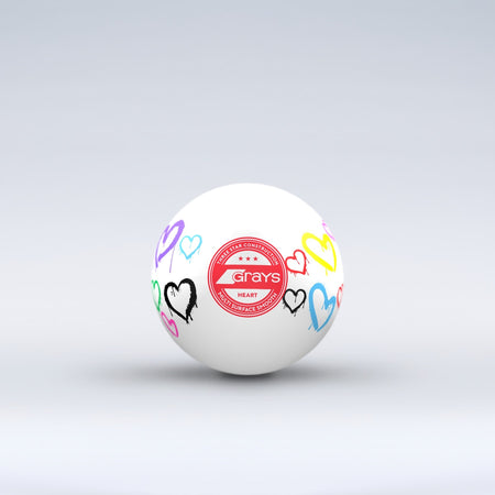 The Grays Novelty Hockey Ball 2026 features a white design with three-star construction, a red central logo, and colorful heart graphics—an eye-catching choice for any hockey player.