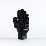 The Grays International Pro Hockey Glove by Grays, in black, is shown standing upright on a plain white background. It features a lycra palm, thick segmented cushioning on the back, Velcro wrist strap, and an orange and white logo.
