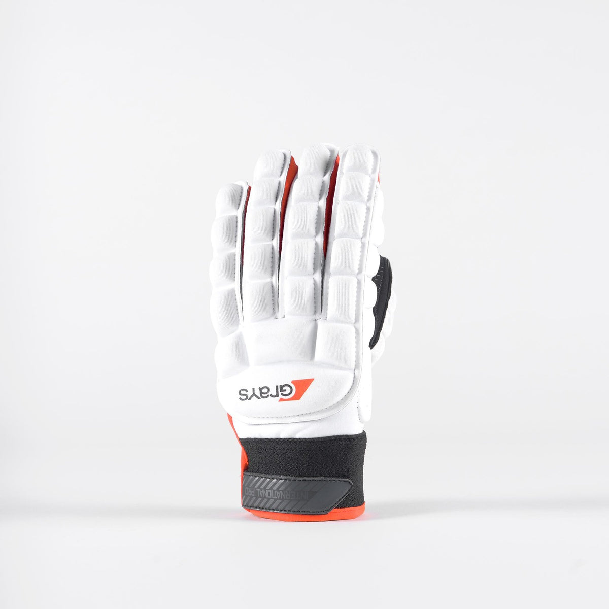 The Grays International Pro Hockey Glove in white stands upright, showcasing full-finger coverage, black and red accents, finger padding, and a lycra palm for flexible, all-weather grip.