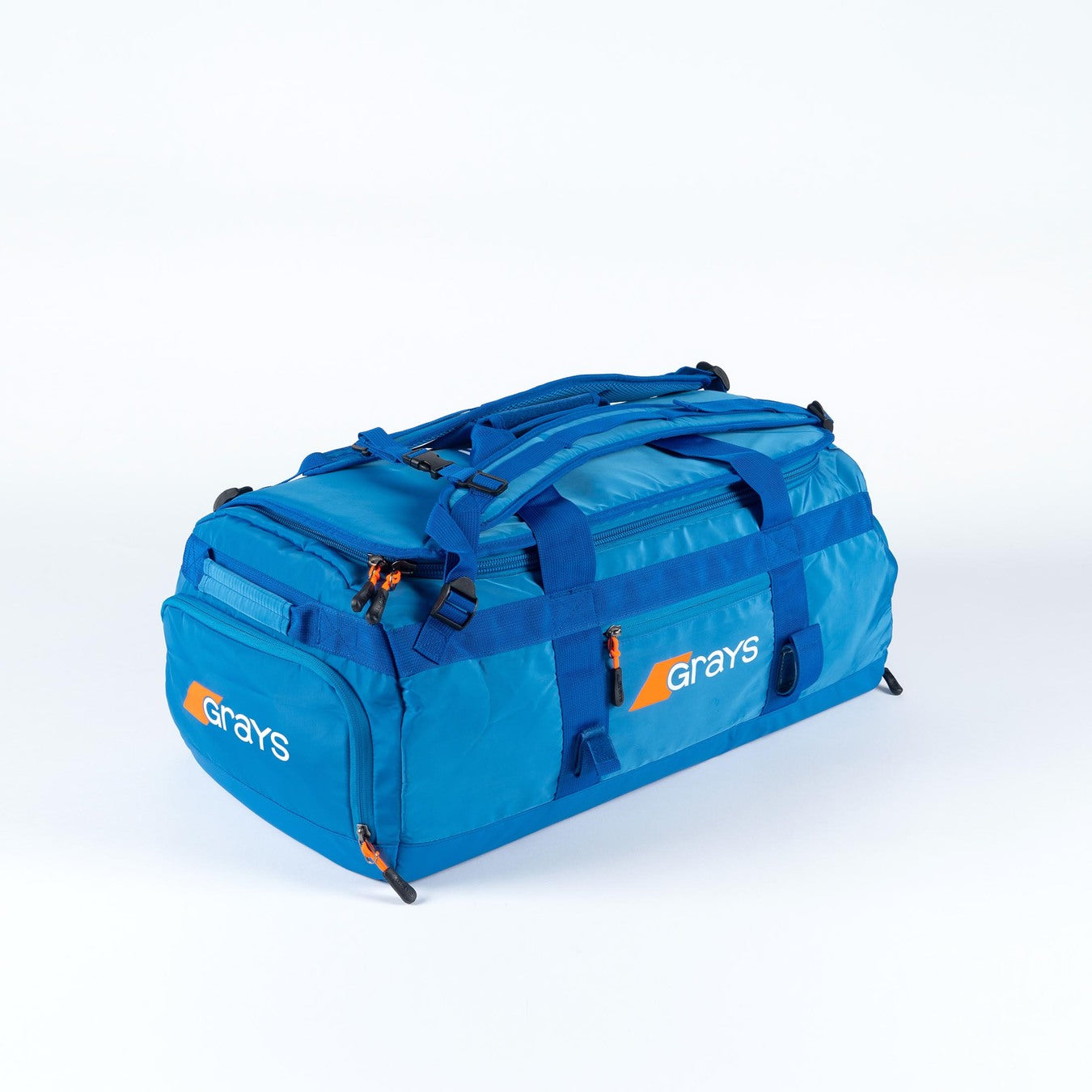 The Grays Omega Gen 4 Holdall is a spacious blue hockey gear bag with the Grays logo in white and orange, multiple zippered compartments, handles, adjustable shoulder straps, and a stick-ready design—ideal for pro players.