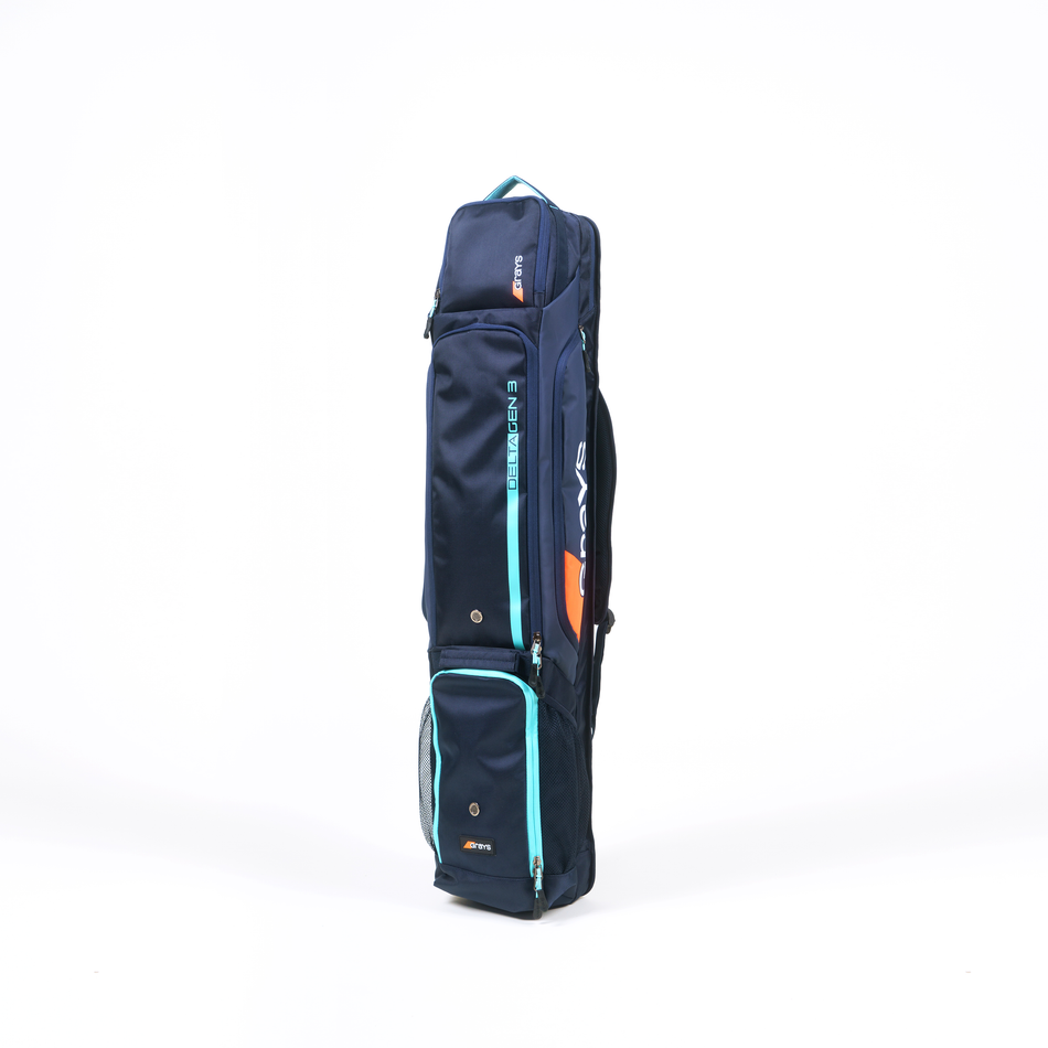 The Grays Delta Gen3 Hockey Kitbag by Grays, shown in Navy/Aqua, stands upright on a white background and features multiple compartments, padded handles, and a padded stick section for secure storage.