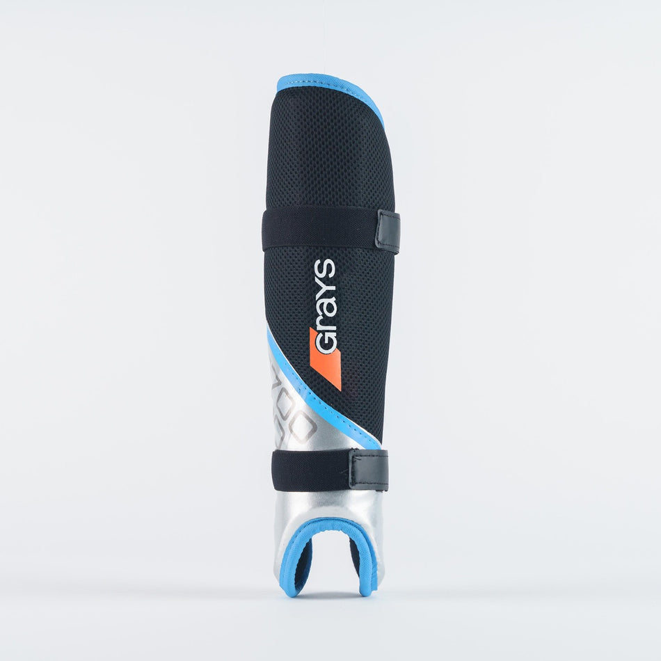 The Grays G700 Pro Shinguards by Grays are black/sky, feature an anatomical fit, two black straps, a sculptured hard outer shell, blue trim, and display the Grays logo vertically on the front.