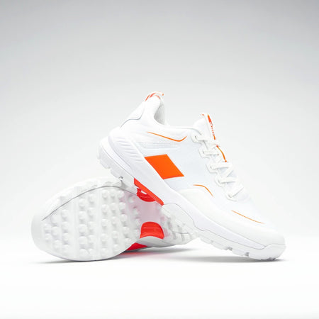 The Grays Aero Cage X Hockey Shoes by Grays are white athletic shoes with bright orange accents and a genius foam midsole for lightweight comfort. Displayed on a plain background, one shoe is upright and the other lies on its side.
