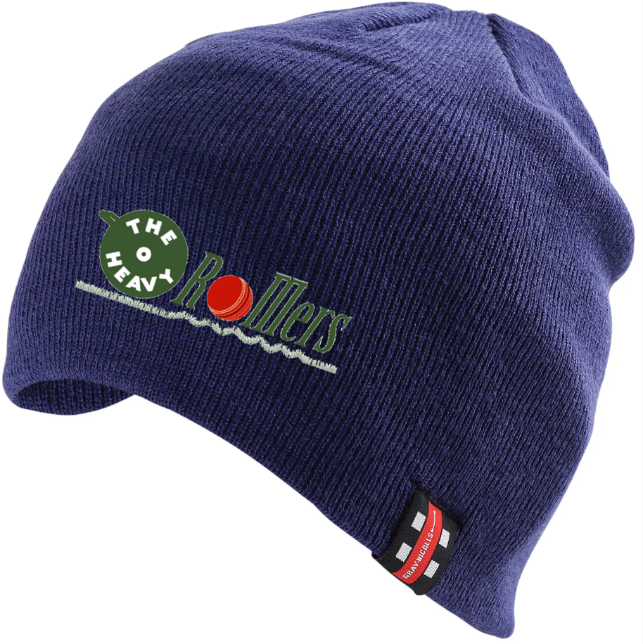 The Gray Nicolls Heavy Rollers CC Beanie Hat is navy blue, made from 100% acrylic stretch fabric, and features The Heavy Rollers logo with a green bowling ball and red pin on the front, plus a black-and-red tag on the brim.