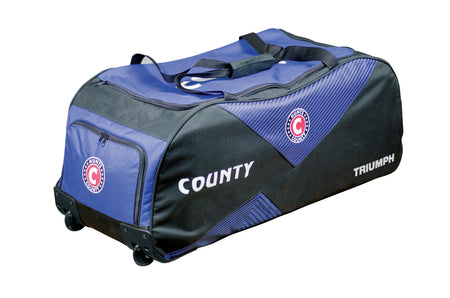 The Hunts County Triumph Wheelie is a large black and blue cricket bag with wheelies, featuring the circular C logo on the side and front pocket. Designed by Hunts County, it offers handles for easy carrying and ample storage for all your gear.