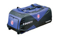 The Hunts County Triumph Wheelie is a large black and blue cricket bag with wheelies, featuring the circular C logo on the side and front pocket. Designed by Hunts County, it offers handles for easy carrying and ample storage for all your gear.