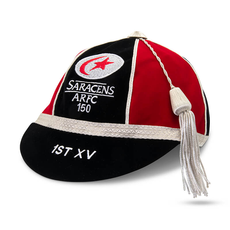 Martin Berrill Sports' Custom, Honour & Commemorative Caps feature black and red velvet, white trim, a long white tassel, and "Saracens ARFC 150" plus "1st XV" embroidery—ideal as an honour cap or bespoke cricket cap.