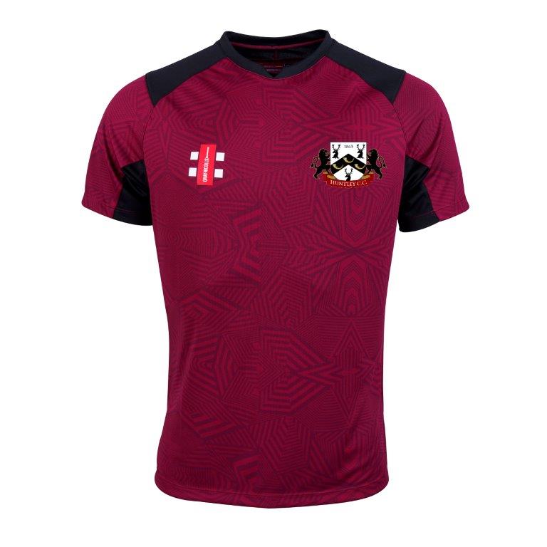 The Gray Nicolls Huntley CC Pro T20 Short Sleeve Match Shirt is maroon with black shoulder and sleeve accents, a geometric pattern, a white and red logo on the right chest, and a lion-and-castle crest on the left.