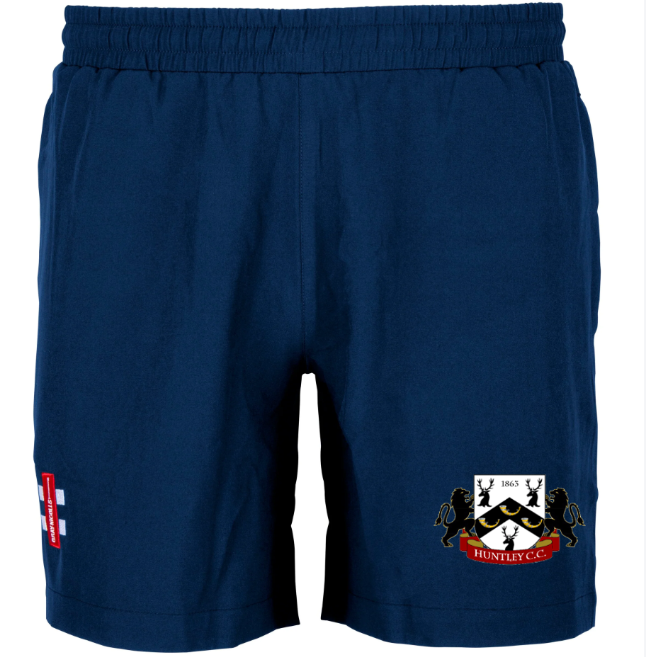 The Gray Nicolls Huntley CC Training Shorts (Adult) feature a navy design with a crest of two lions, a red "Huntly C.C." banner, and a white panel with a red cross and three blue lions—ideal durable shorts for cricket training.