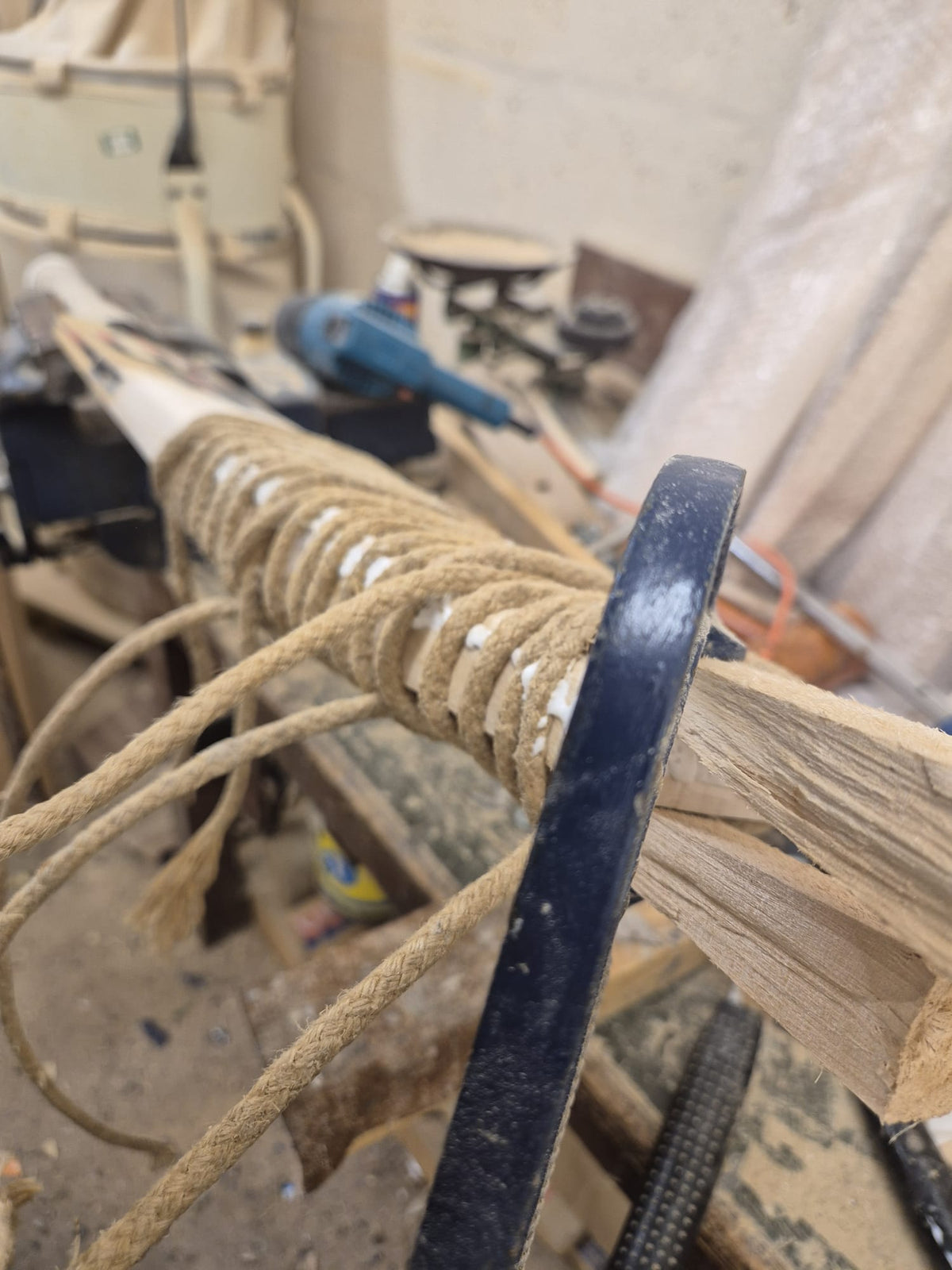 Close-up of a cricket bat being expertly restored at Martin Berrill Sports during their Pre Season & End of Season Clean up, with tools and workbench visible—showcasing craftsmanship akin to sword handle wrapping.